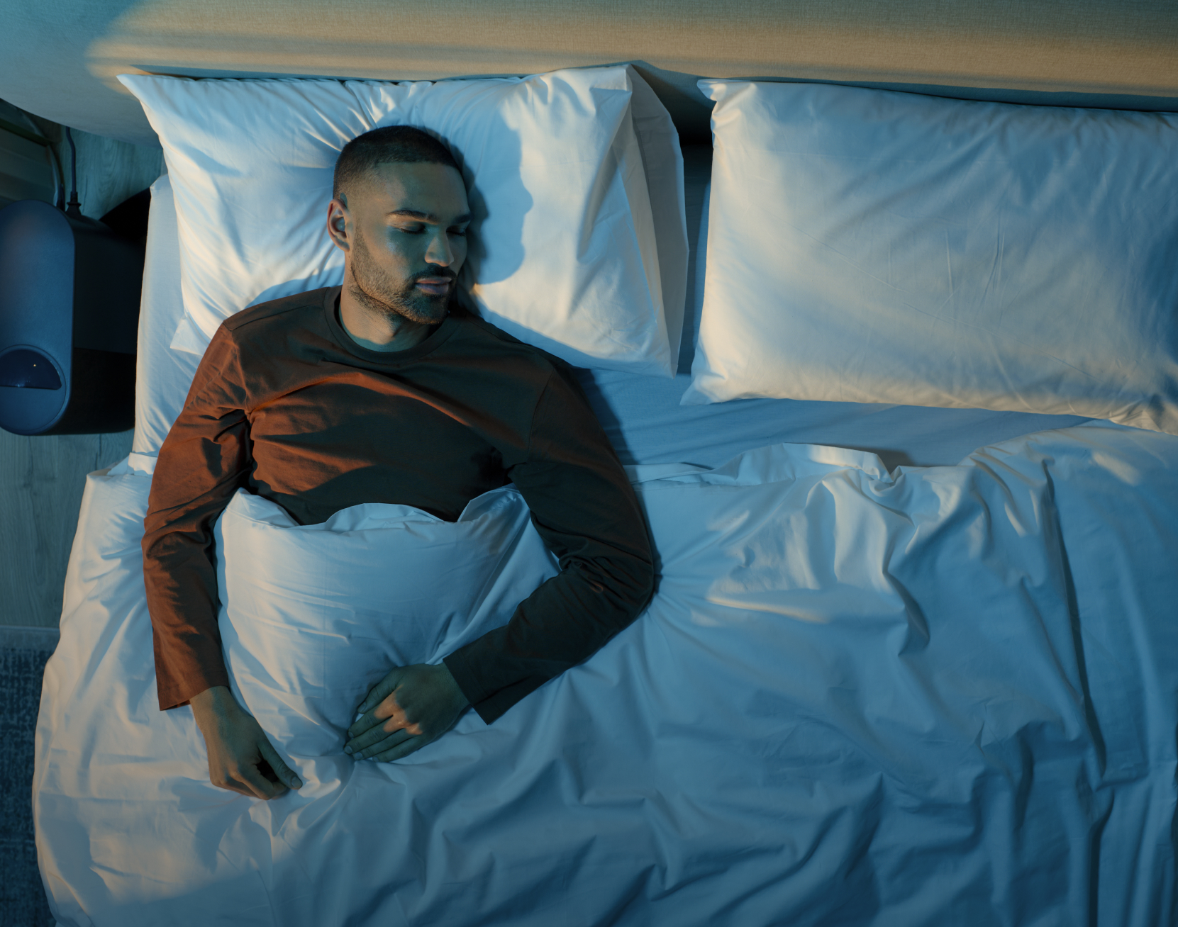 A man sleeping soundly in a cooly lit bedroom