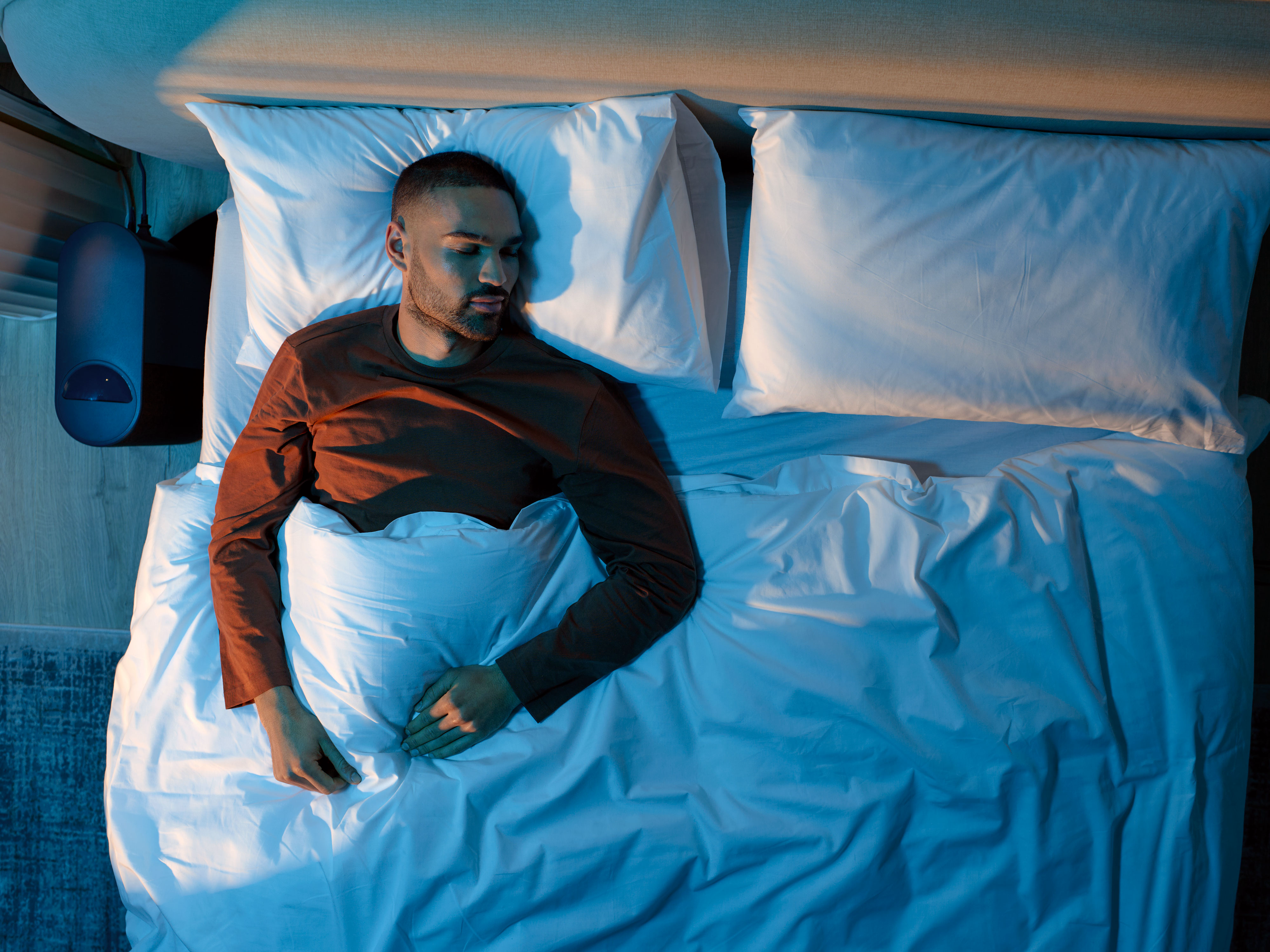 A man sleeping soundly in a cooly lit bedroom